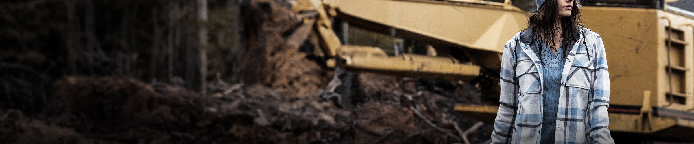 woman wearing jacket standing in front of large construction vehicle